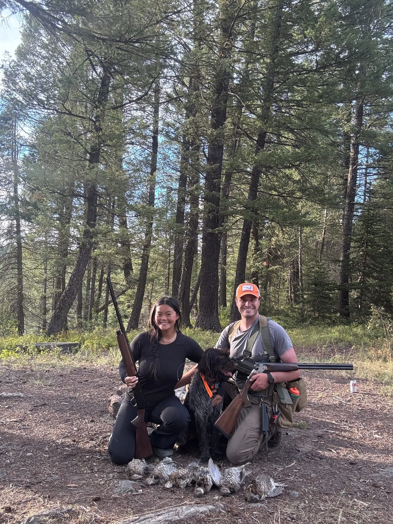 Both hunters and the dog with grouse at camp