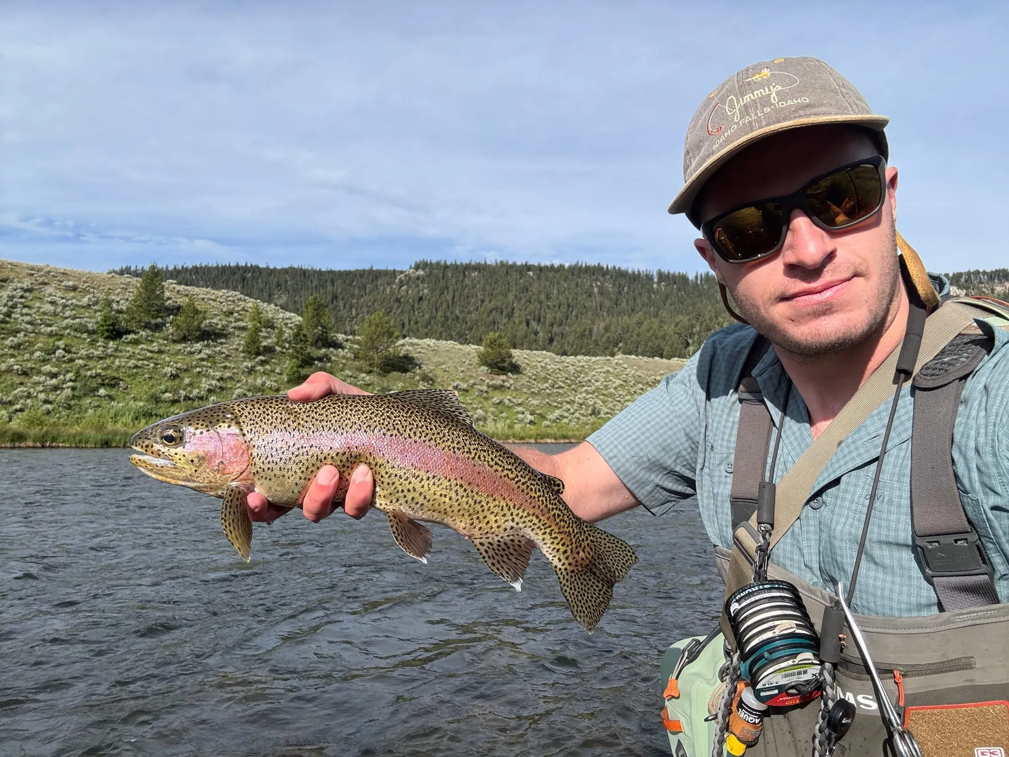 Rainbow trout held over a river