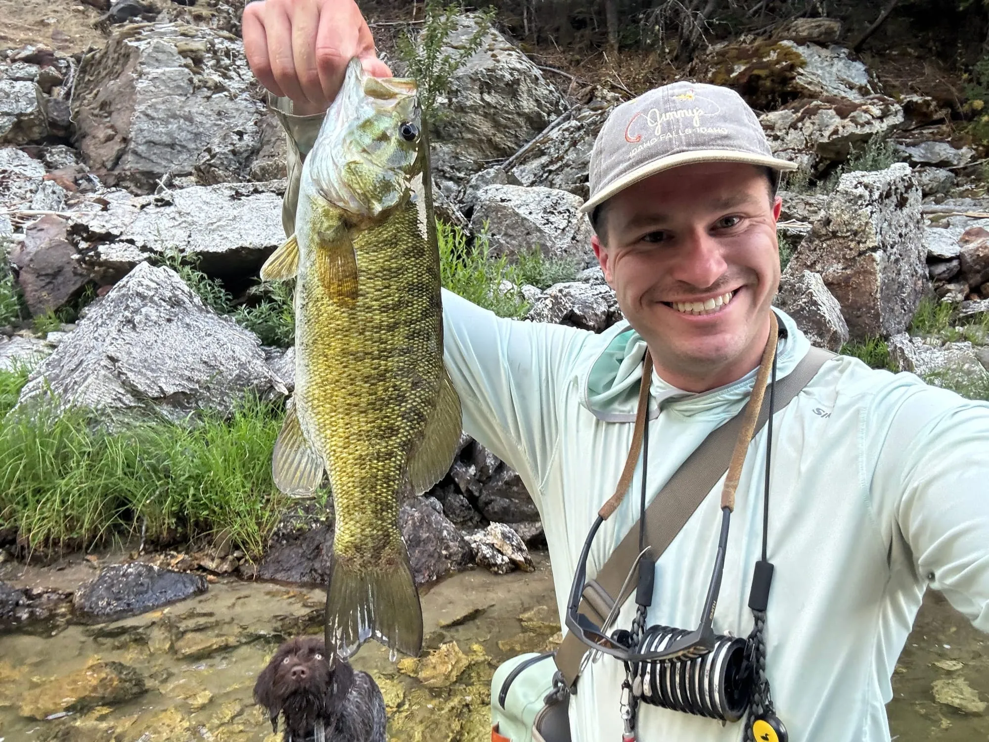 Smallmouth bass held up beside a rocky creek